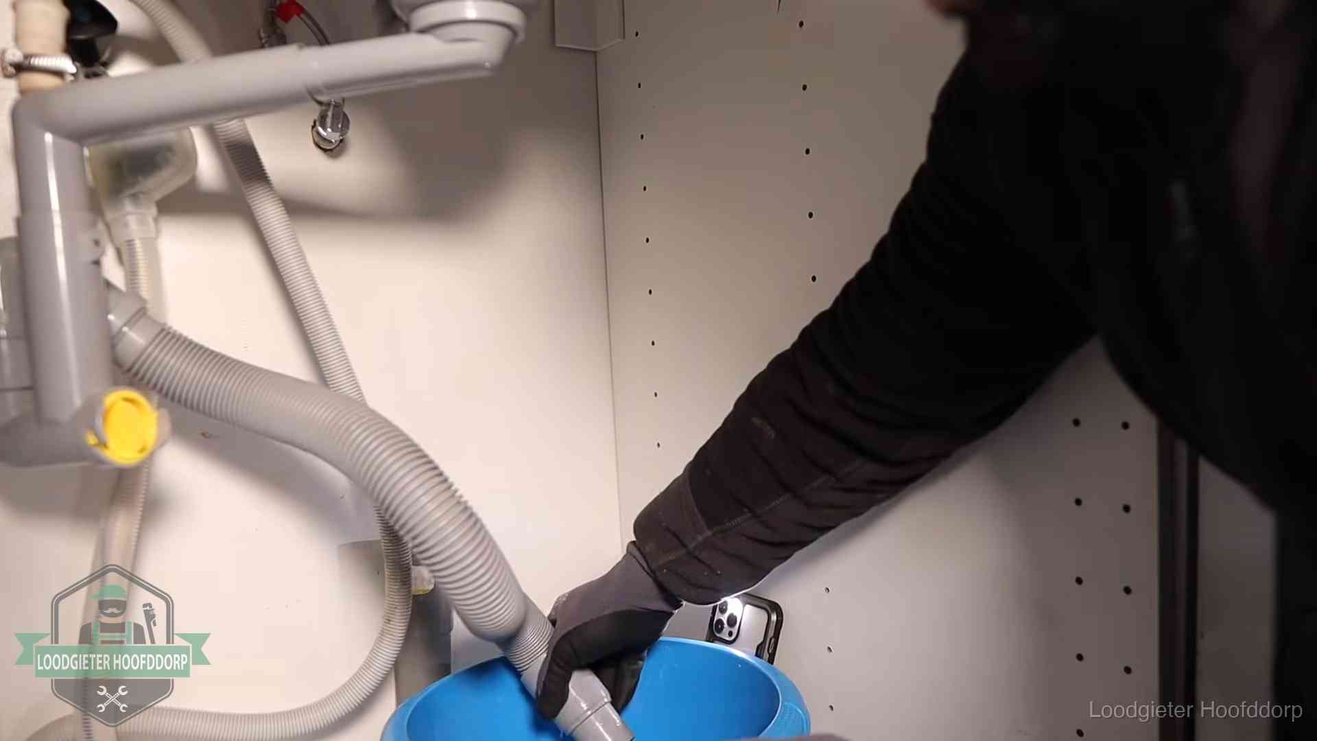 Afvoerslang loopt leeg in een emmer onder de gootsteen in Hoofddorp, een klus die je zelf kunt doen