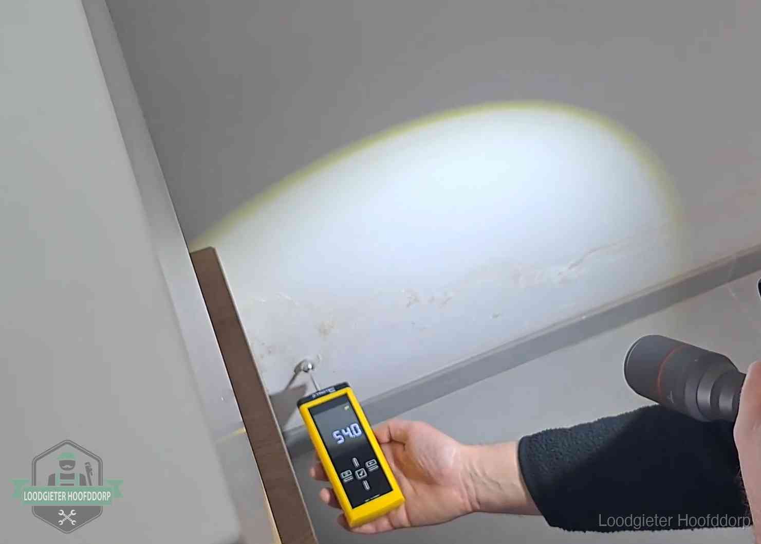 Vochtmeter tegen een natte wand met lekkagesporen in Hoofddorp