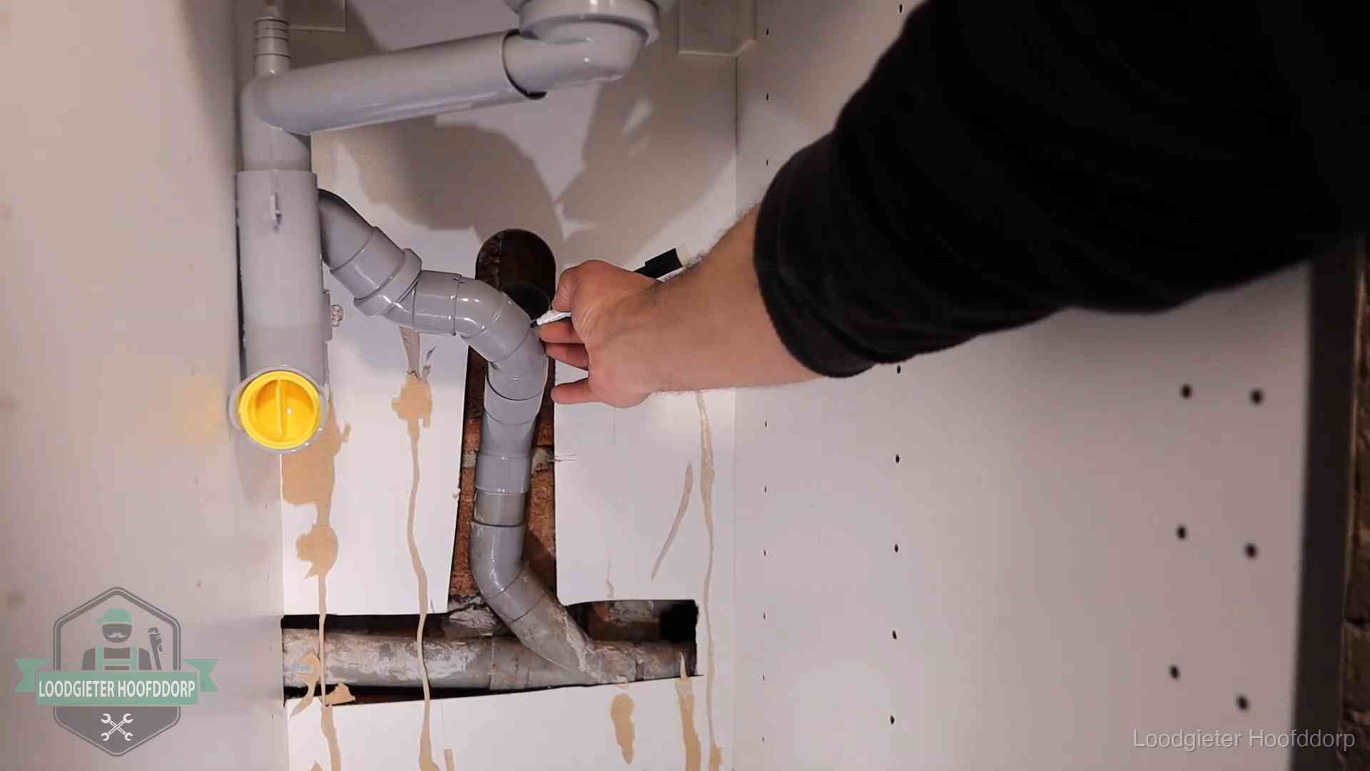 Loodgieter markeert een pvc-afvoerbuis onder een gootsteen in Hoofddorp