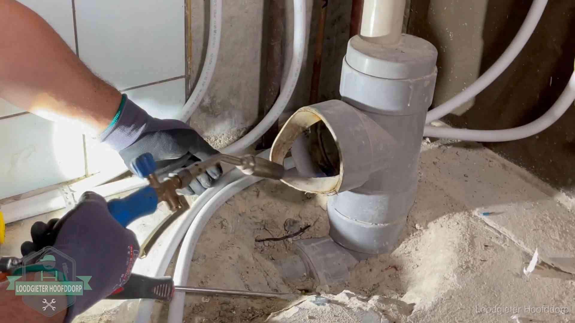 Loodgieter werkt met brander en messing kraanwerk aan leidingen in Hoofddorp