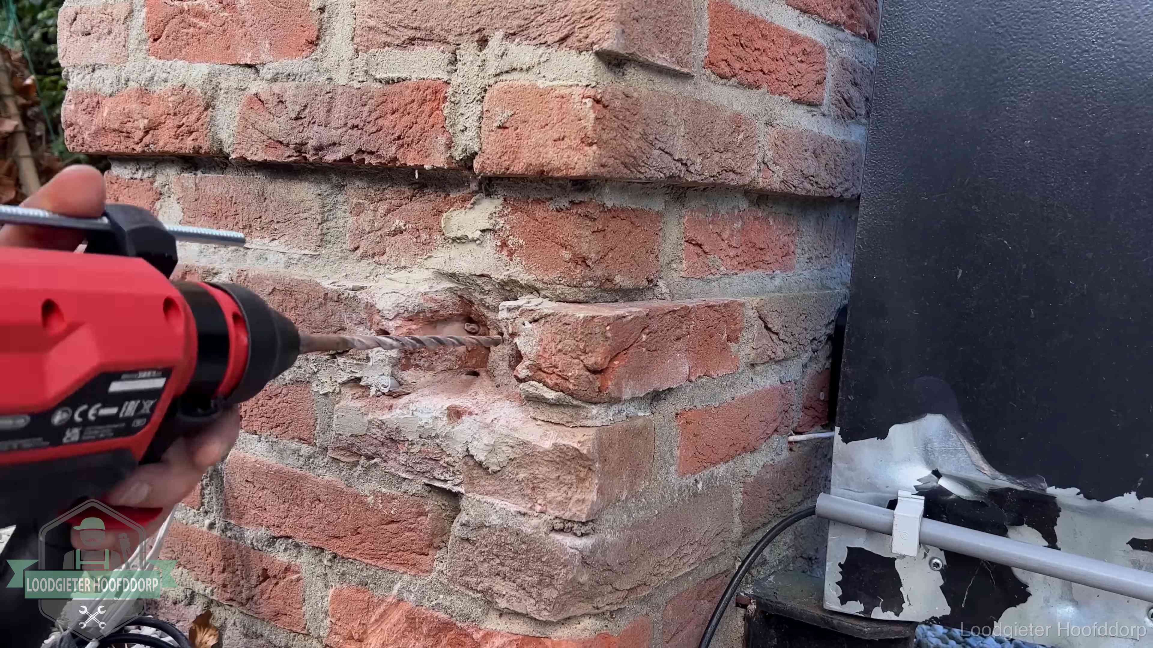 Vakman boort in de buitenmuur van een woning in de regio Hoofddorp