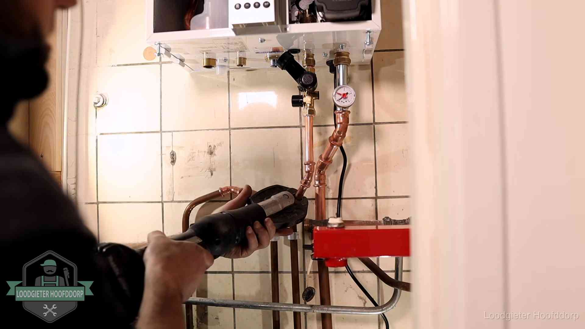 Cv-ketel onderhoud in Hoofddorp Monteur werkt aan de leidingen onder een cv-ketel in Hoofddorp