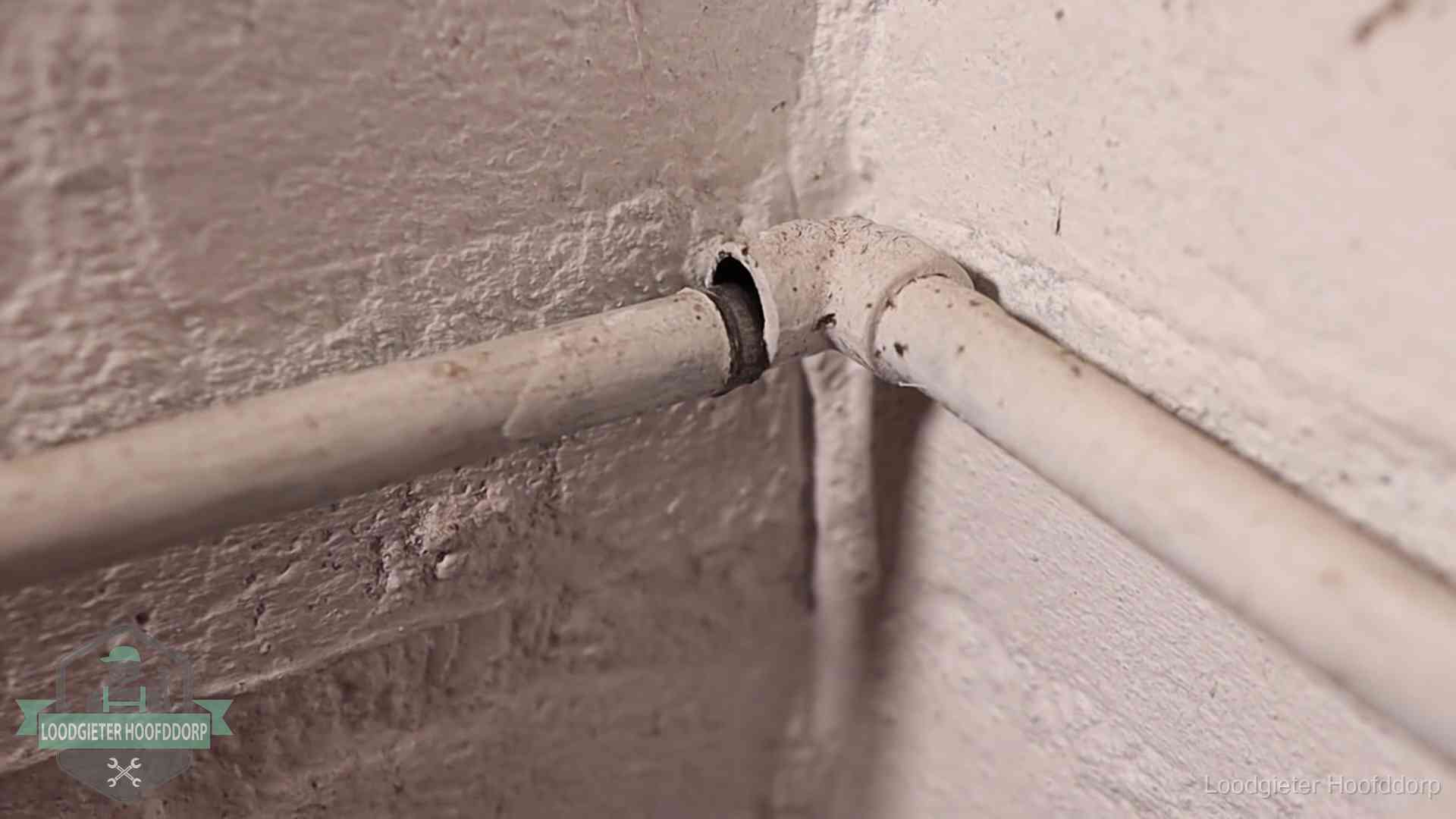 Oude geverfde waterleiding met een losliggende fitting in een woning in Hoofddorp