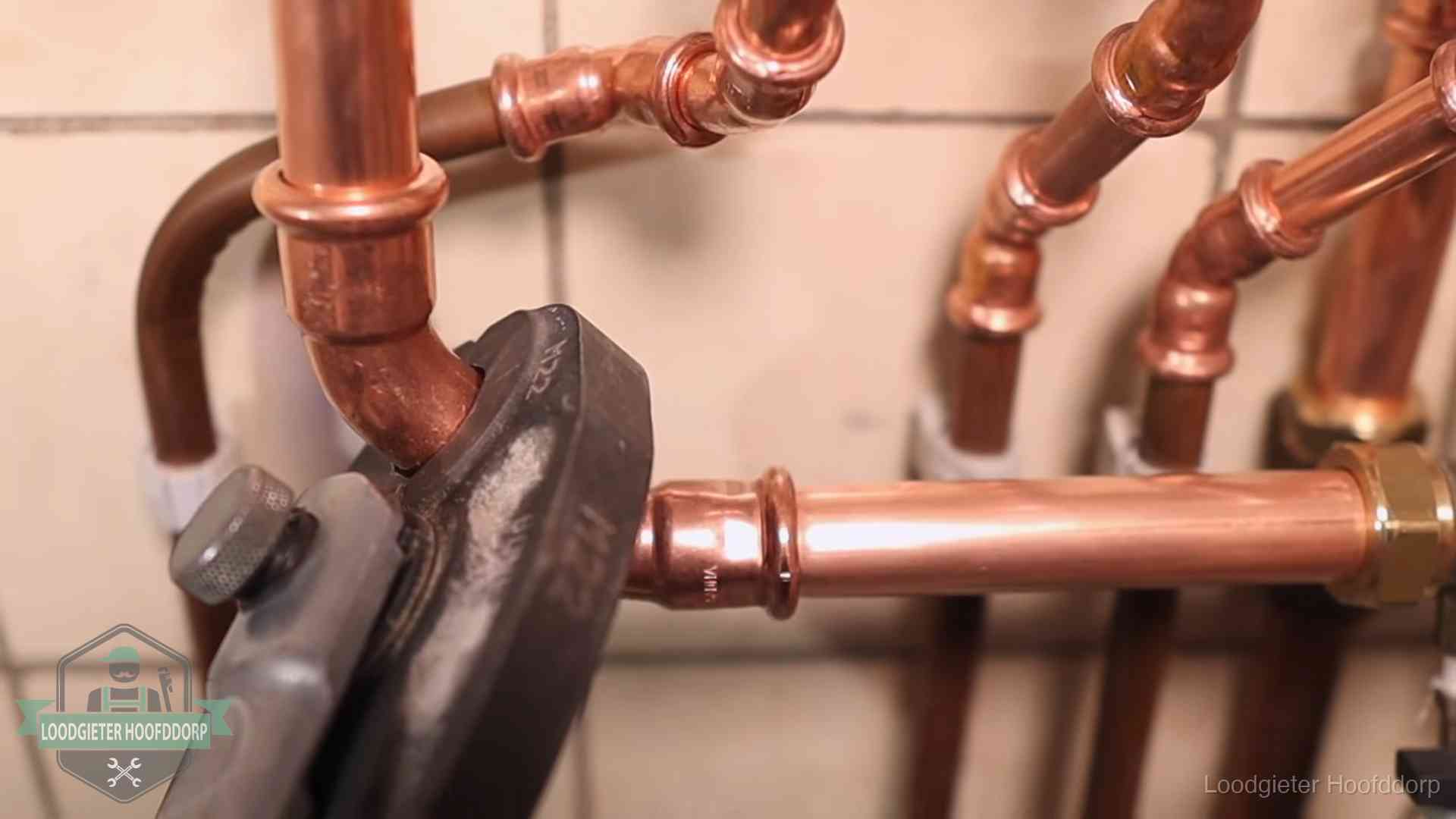 Persmachine perst een koperen fitting op nieuw leidingwerk in Hoofddorp