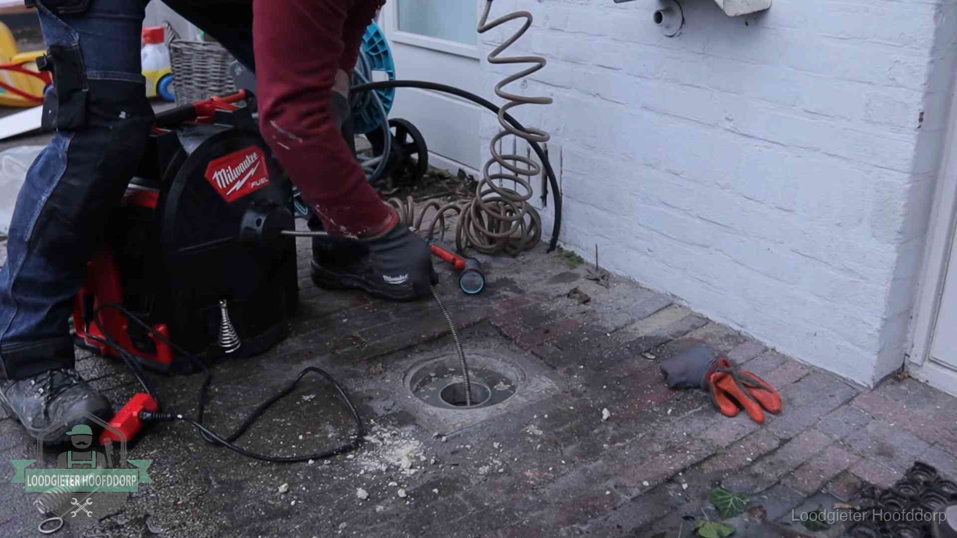 Spiraalmachine bij een ontstoppingsputje in de bestrating in Hoofddorp