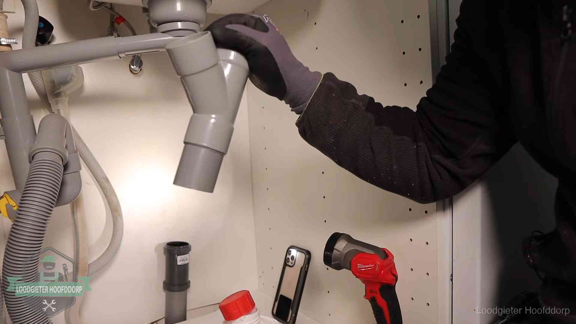Loodgieter demonteert het sifon- en afvoerwerk onder een gootsteen in Hoofddorp bij stankklachten