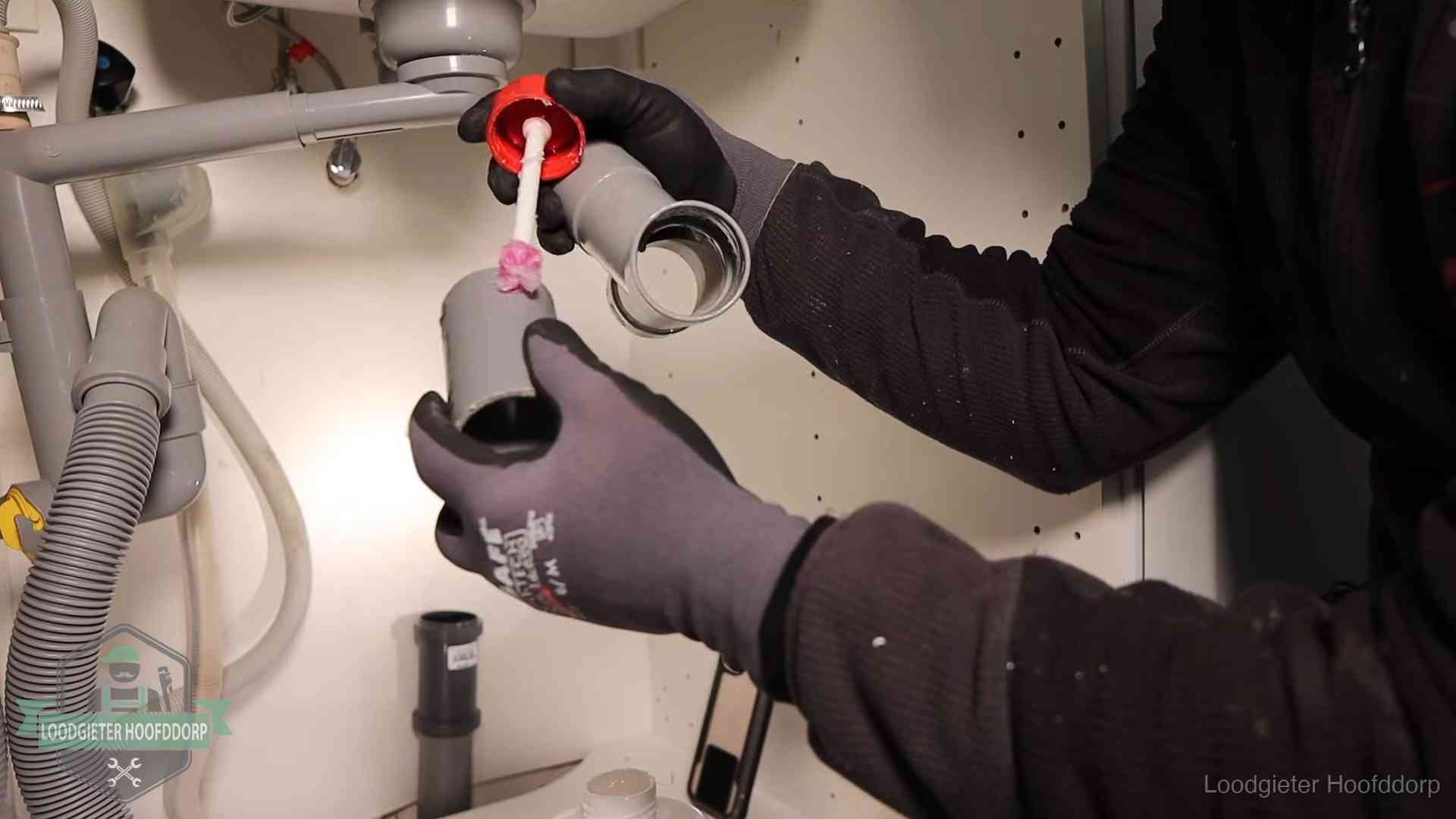 Loodgieter demonteert en reinigt de sifon onder een keukenkast in Hoofddorp