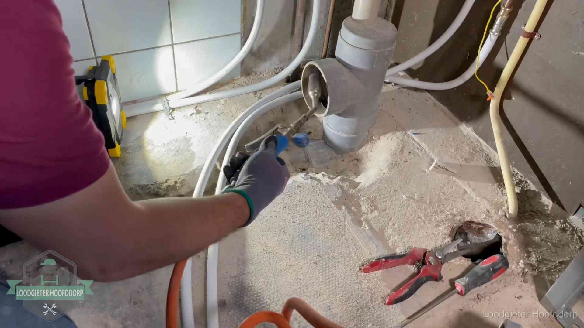 Loodgieter werkt aan leidingen bij een pvc-standleiding in een appartement in Hoofddorp