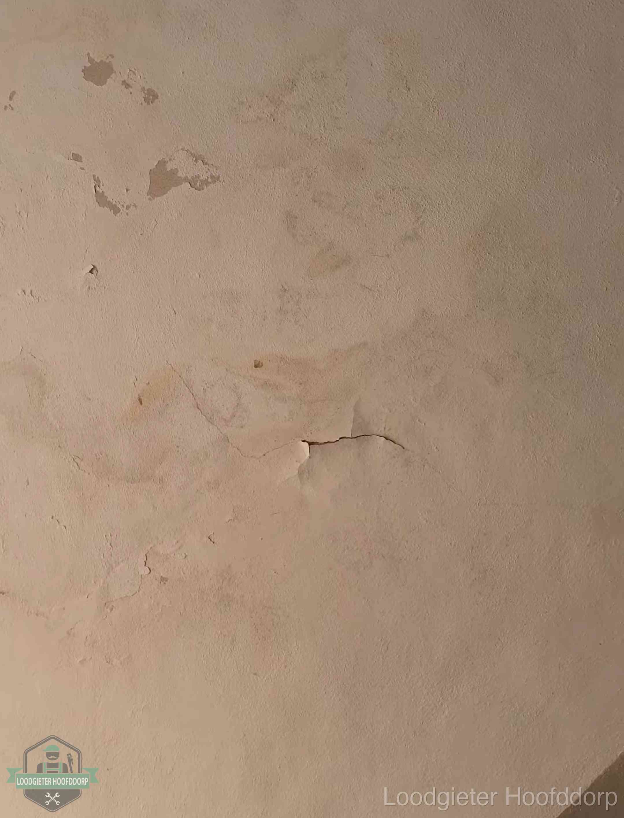 Vochtkringen en afbladderende verf op een plafond in Hoofddorp, schade voor het meetrapport en de verzekering